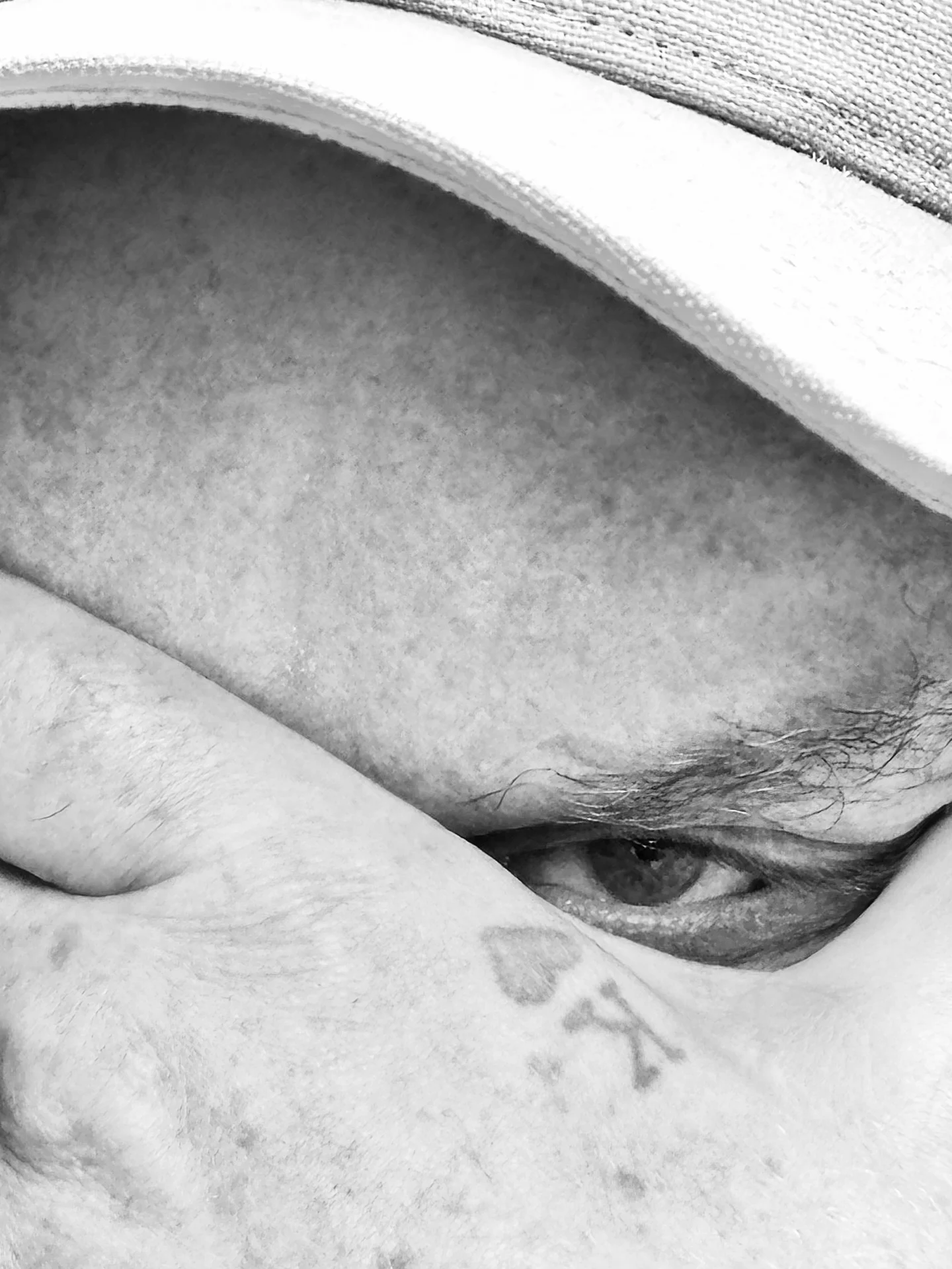 Black and white close-up portrait detail of D.R.L. partially hidden beneath a cap.